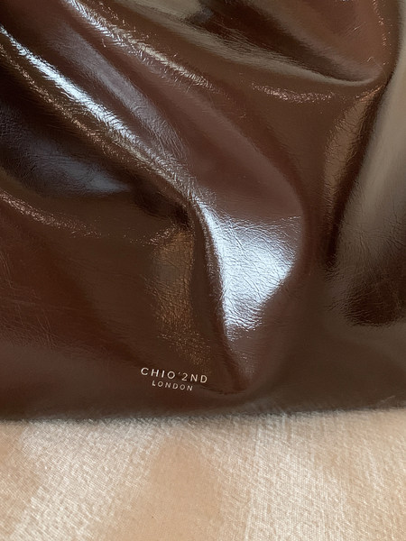 Close-up of a glossy brown leather product with CHIO'2ND LONDON branding