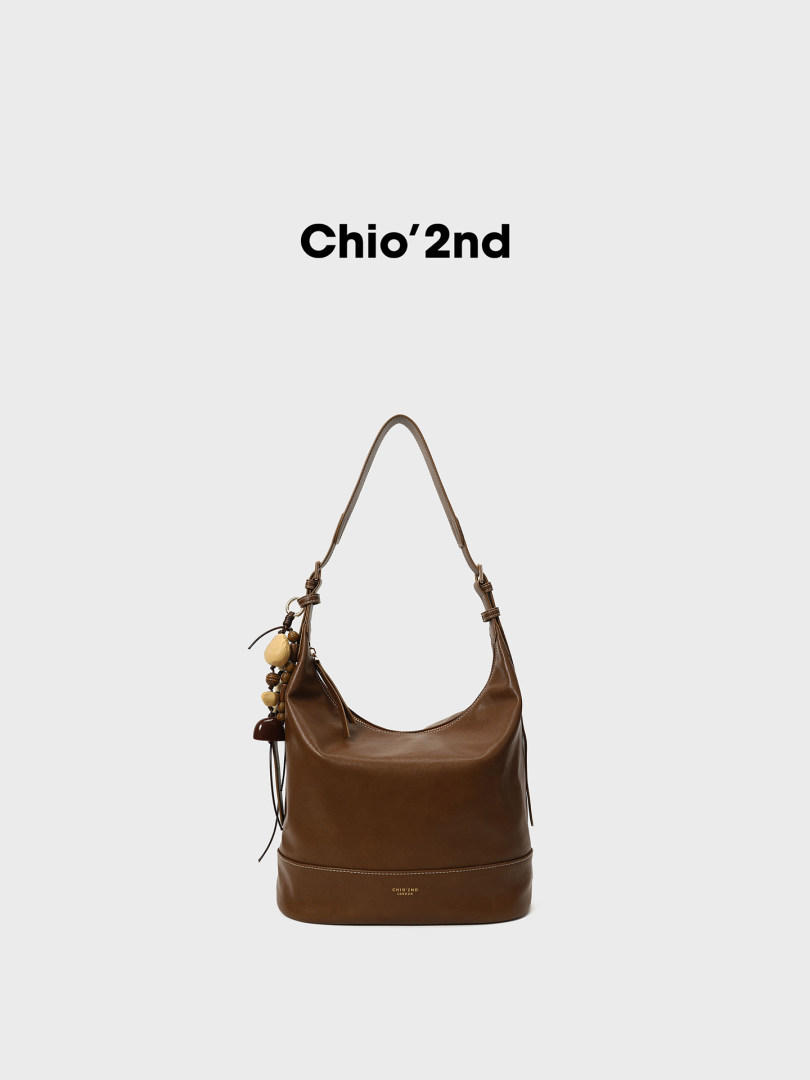 Brown leather shoulder bag with charm detail on a white background