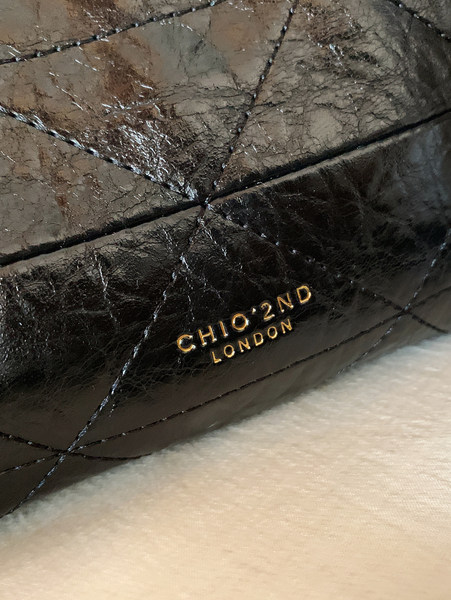 Close-up of a black quilted leather bag with CHIO'2ND LONDON branding