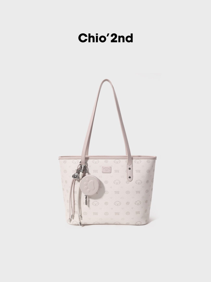 Light pink patterned tote handbag with long straps and charm accessories