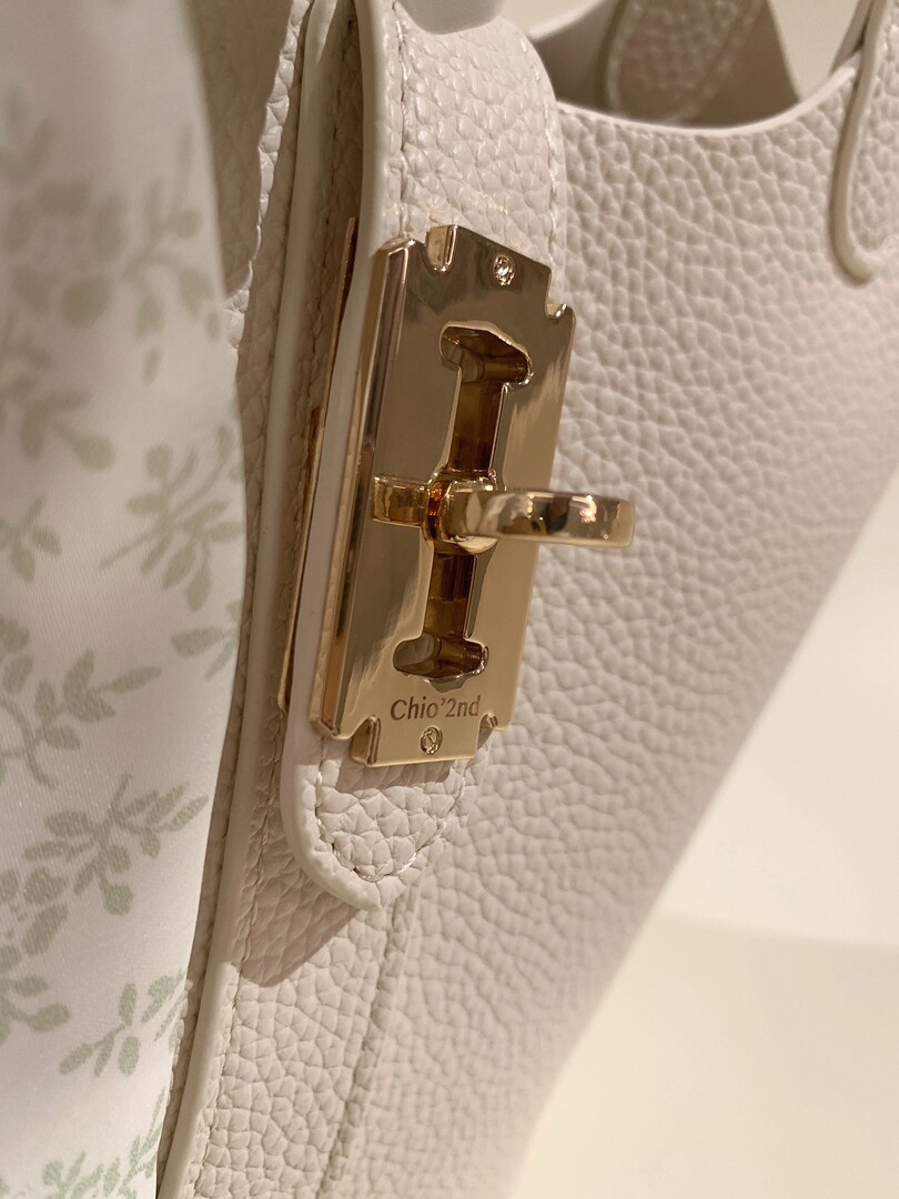 Close-up of a white textured handbag with a gold clasp