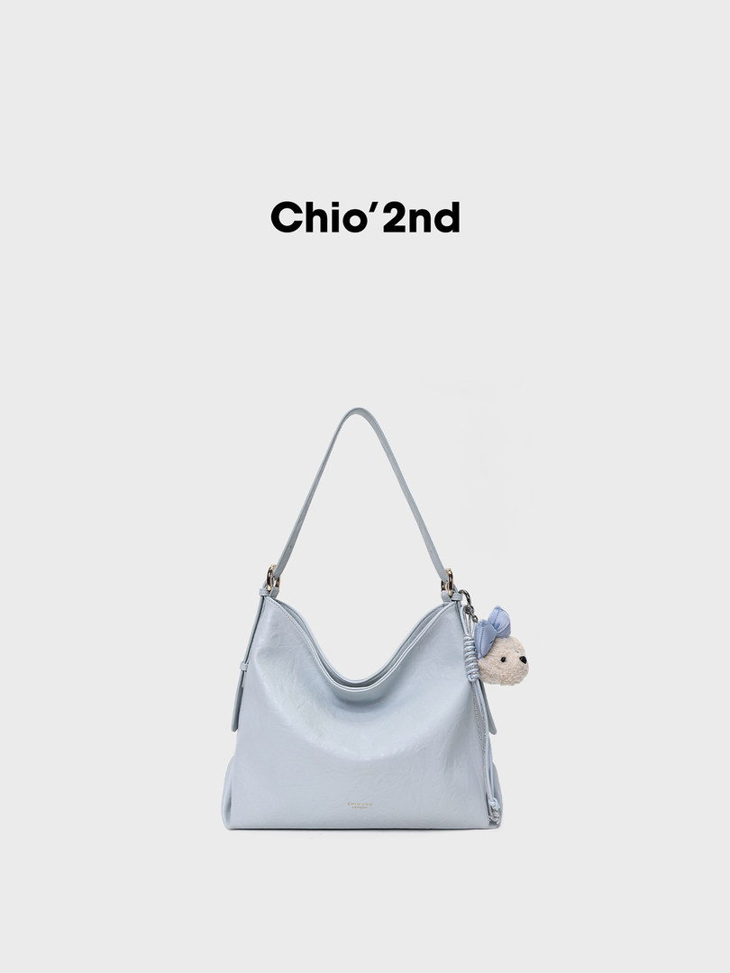 Light blue shoulder handbag with teddy charm on a white background