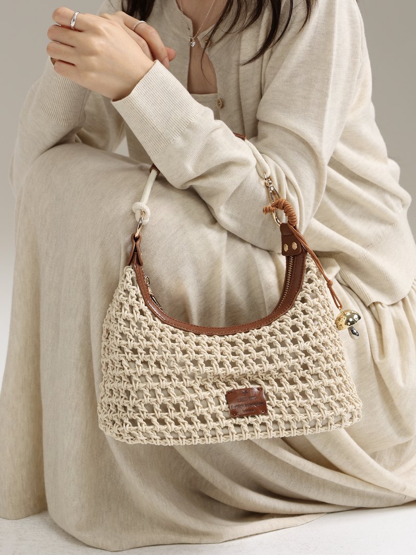 Cream woven handbag with brown leather trim held by a model