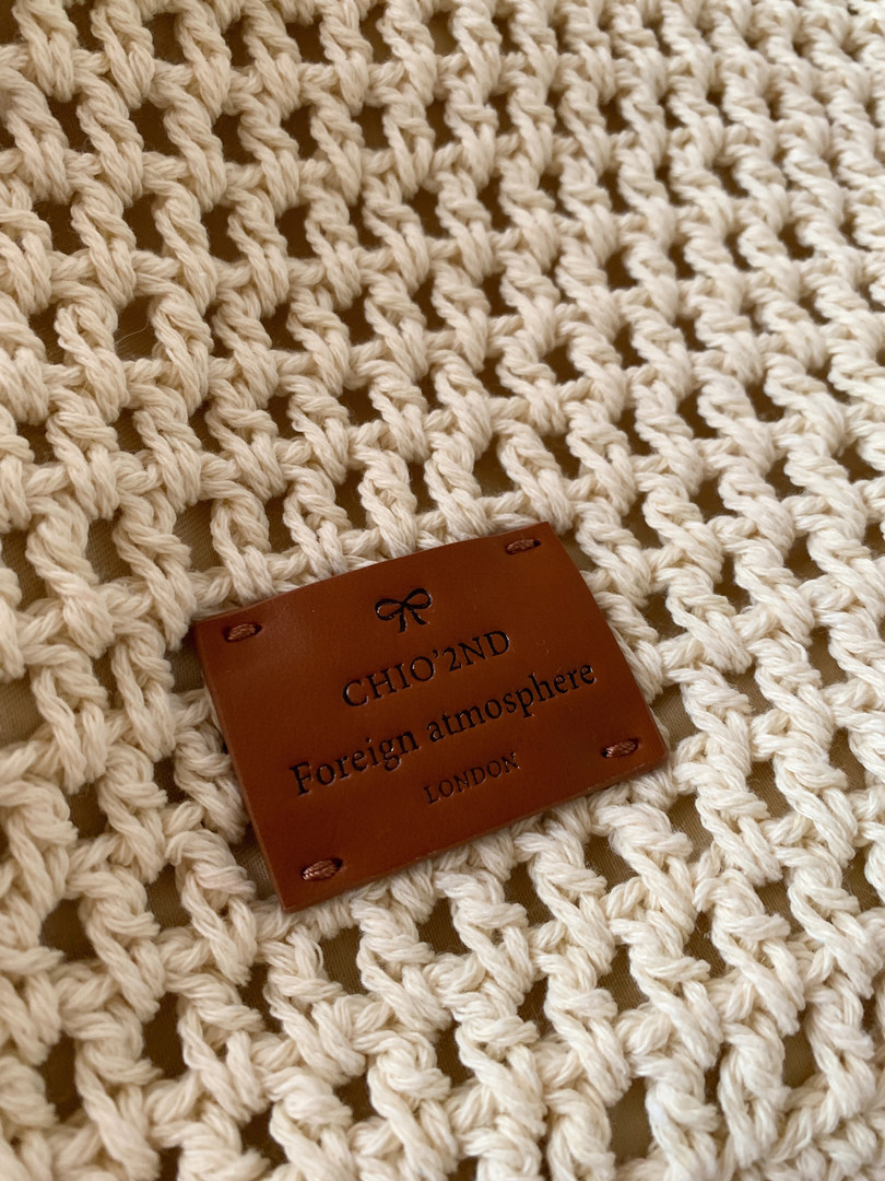 Cream crocheted knit fabric with a brown brand label