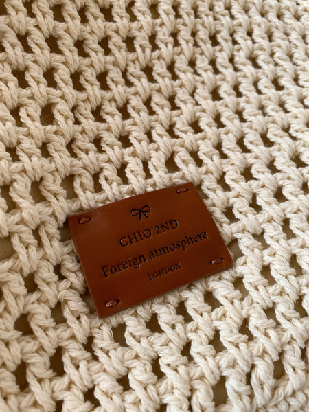 Cream crocheted knit fabric with a brown brand label