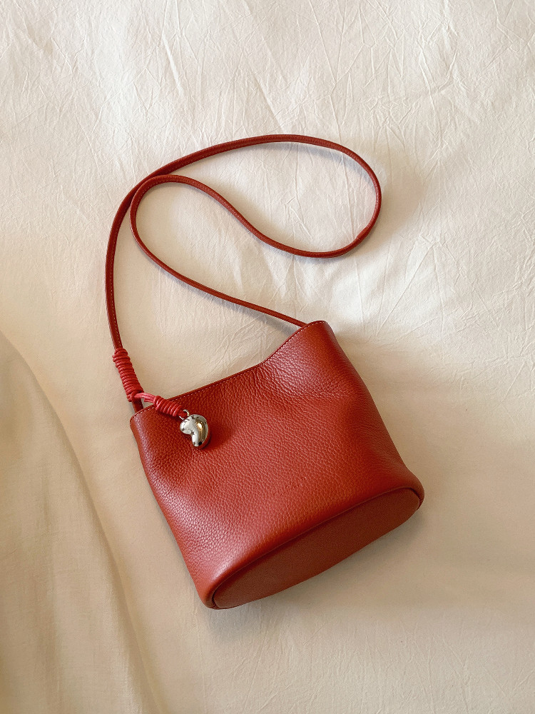 Red leather crossbody handbag on a light fabric background