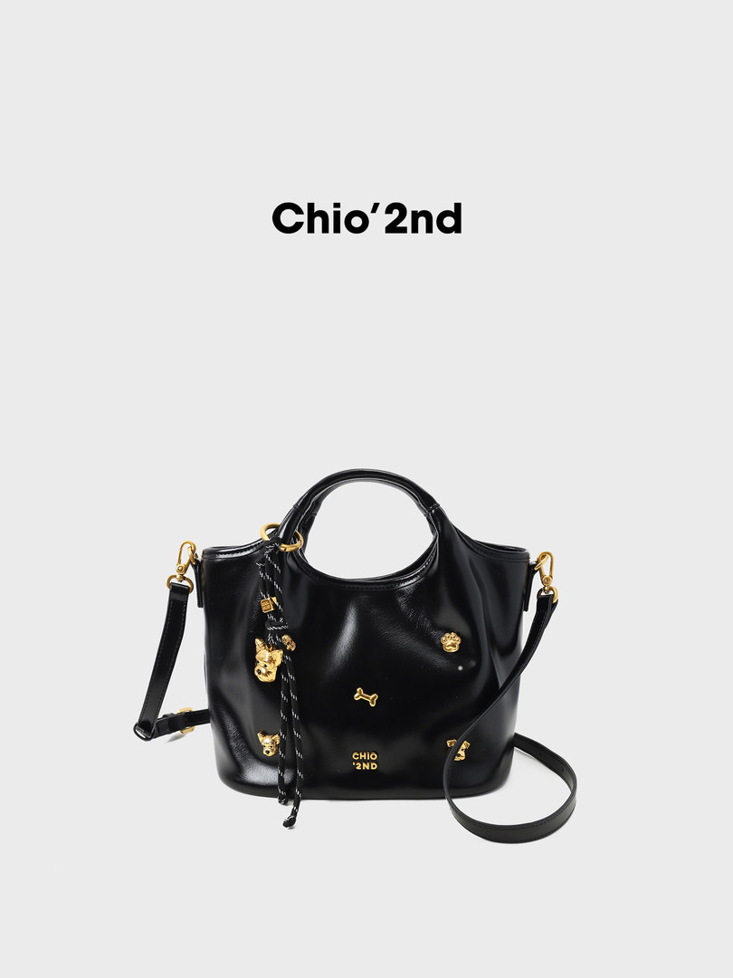 Black leather handbag with gold-tone accents and shoulder strap on a plain background