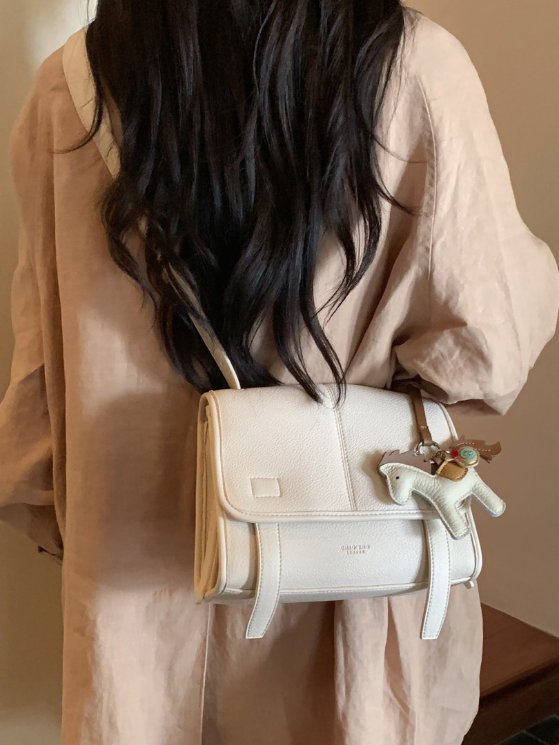 White leather crossbody handbag worn with a beige outfit