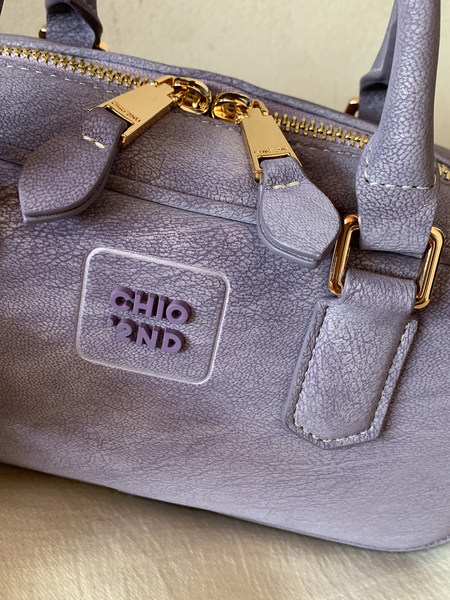 Close-up of a lavender leather handbag with gold hardware