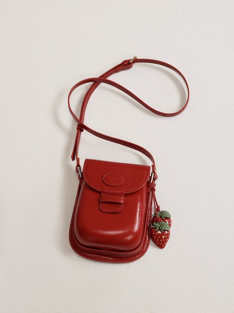Red crossbody mini bag with strawberry charm on a white background