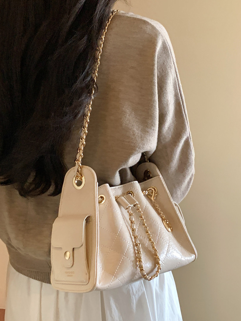 Light beige quilted chain-strap handbag worn on a shoulder