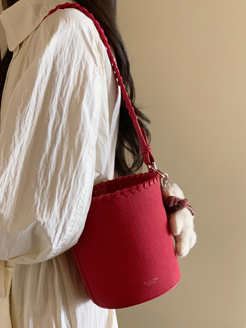 Red bucket handbag worn over a white outfit on a model