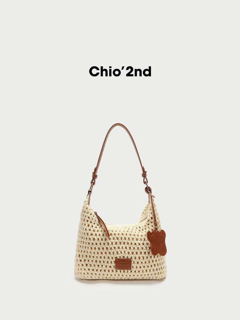 Cream crochet shoulder bag with brown leather strap on white background