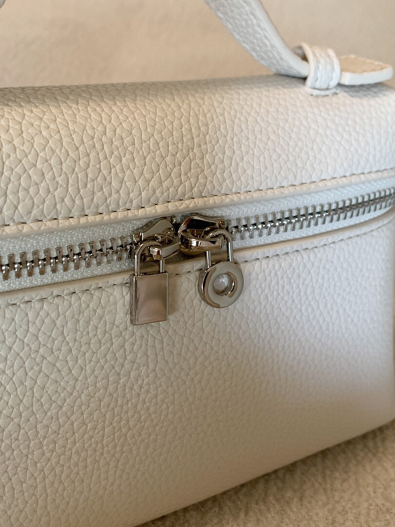 Close-up of a cream textured handbag with zipper and lock