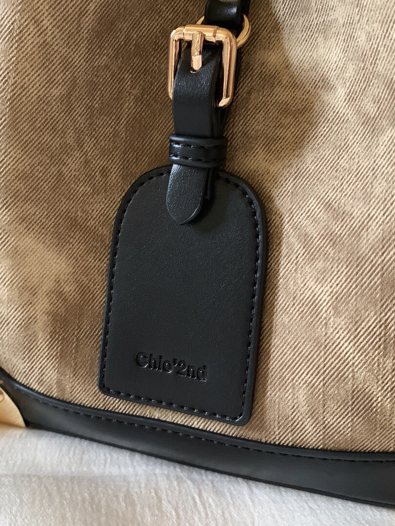 Close-up of a black leather handbag with gold buckle and Chloé tag
