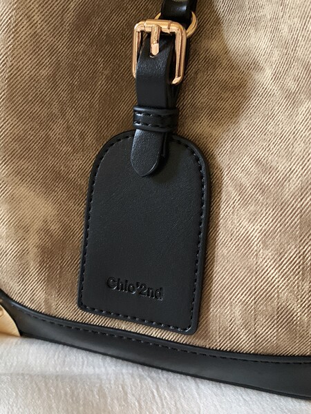 Close-up of a black leather handbag with gold buckle and Chloé tag