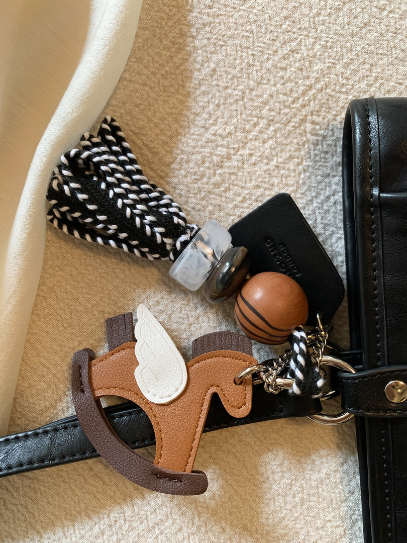 Close-up of a black leather bag strap with decorative charm and tassel