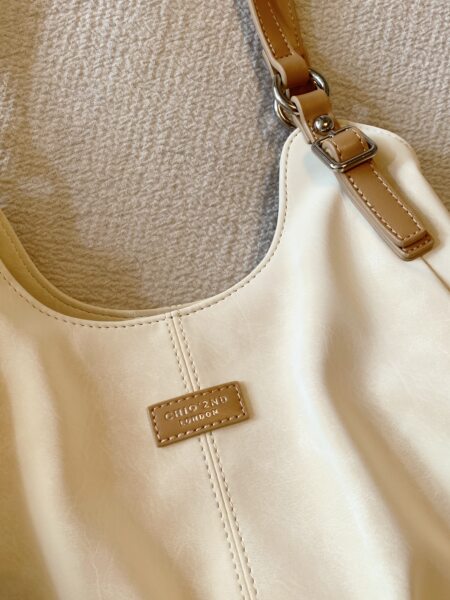 Beige leather handbag with tan strap and metal hardware