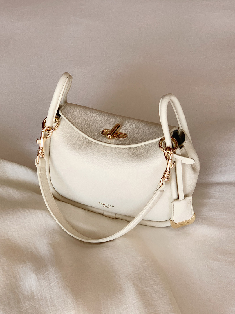 White leather handbag with gold hardware and shoulder strap