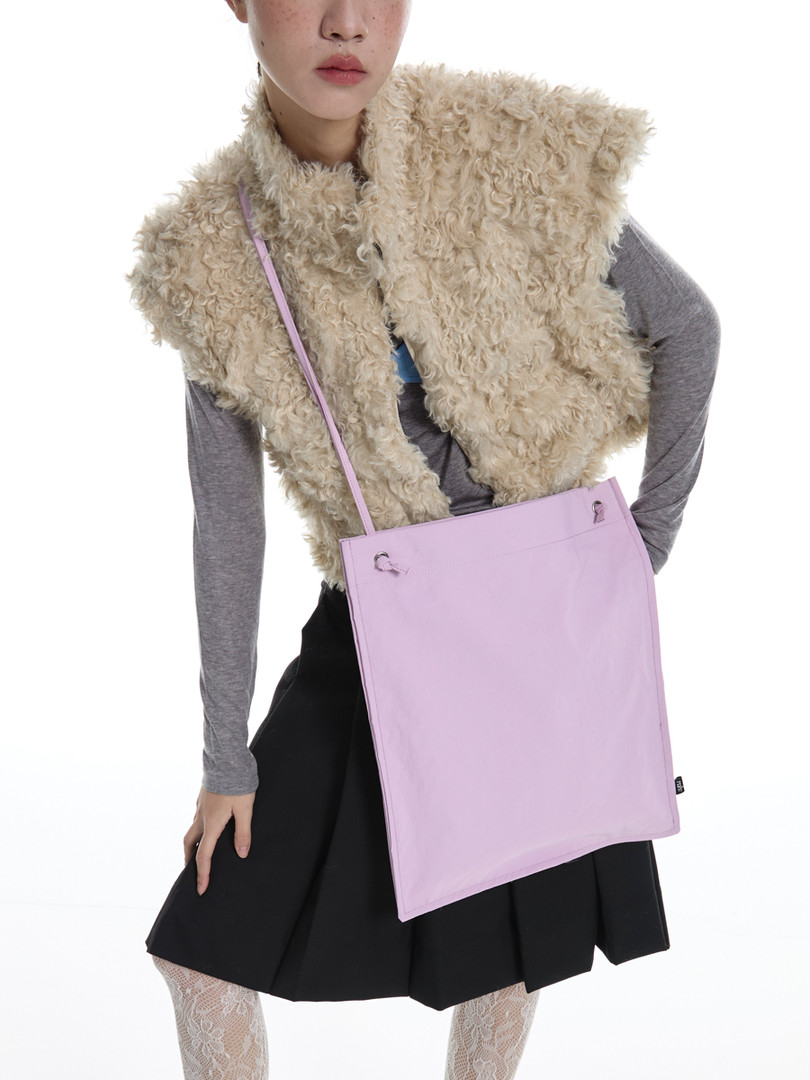 Fashion model wearing a shaggy beige vest and lavender crossbody tote bag