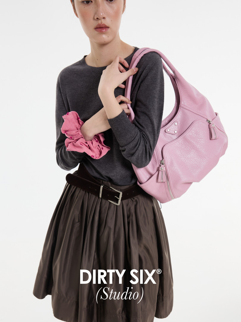 Model wearing a dark top and skirt with a pink shoulder bag