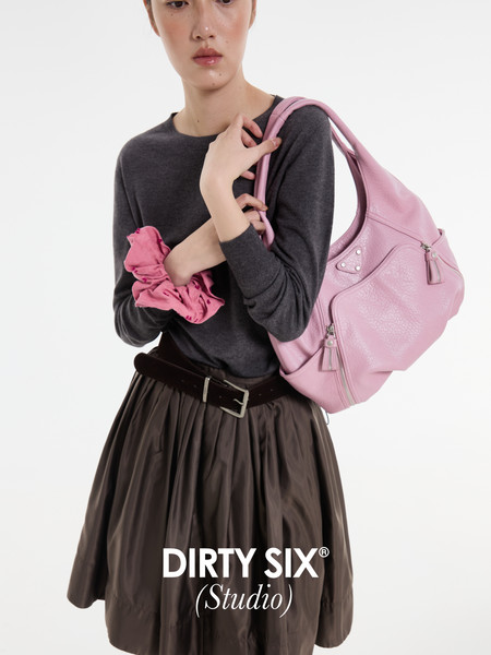 Model wearing a dark top and skirt with a pink shoulder bag