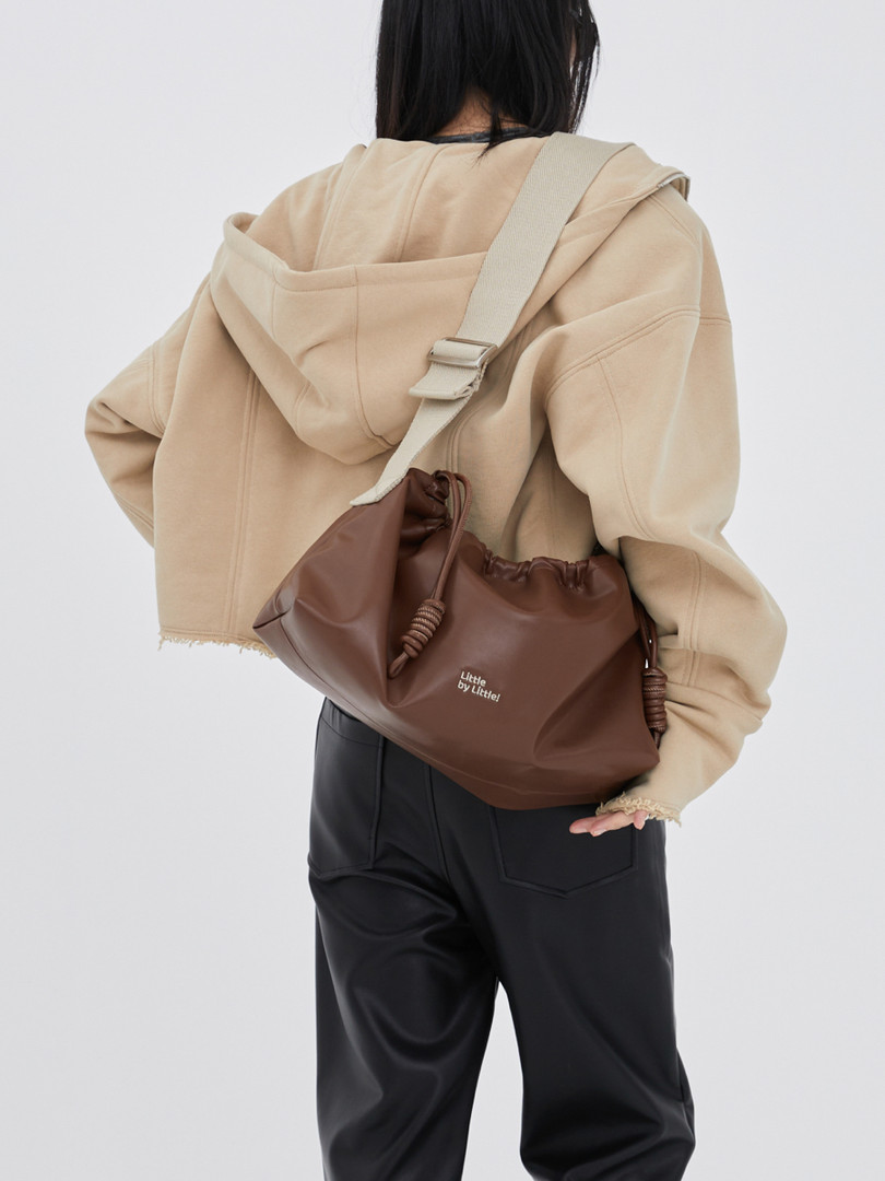 Brown drawstring shoulder bag worn crossbody on a model