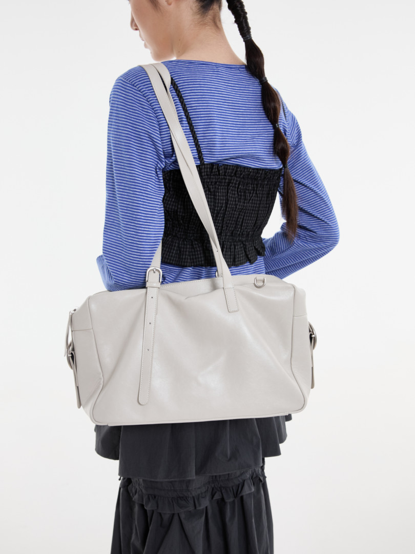 Model wearing a large light gray tote bag over a striped top