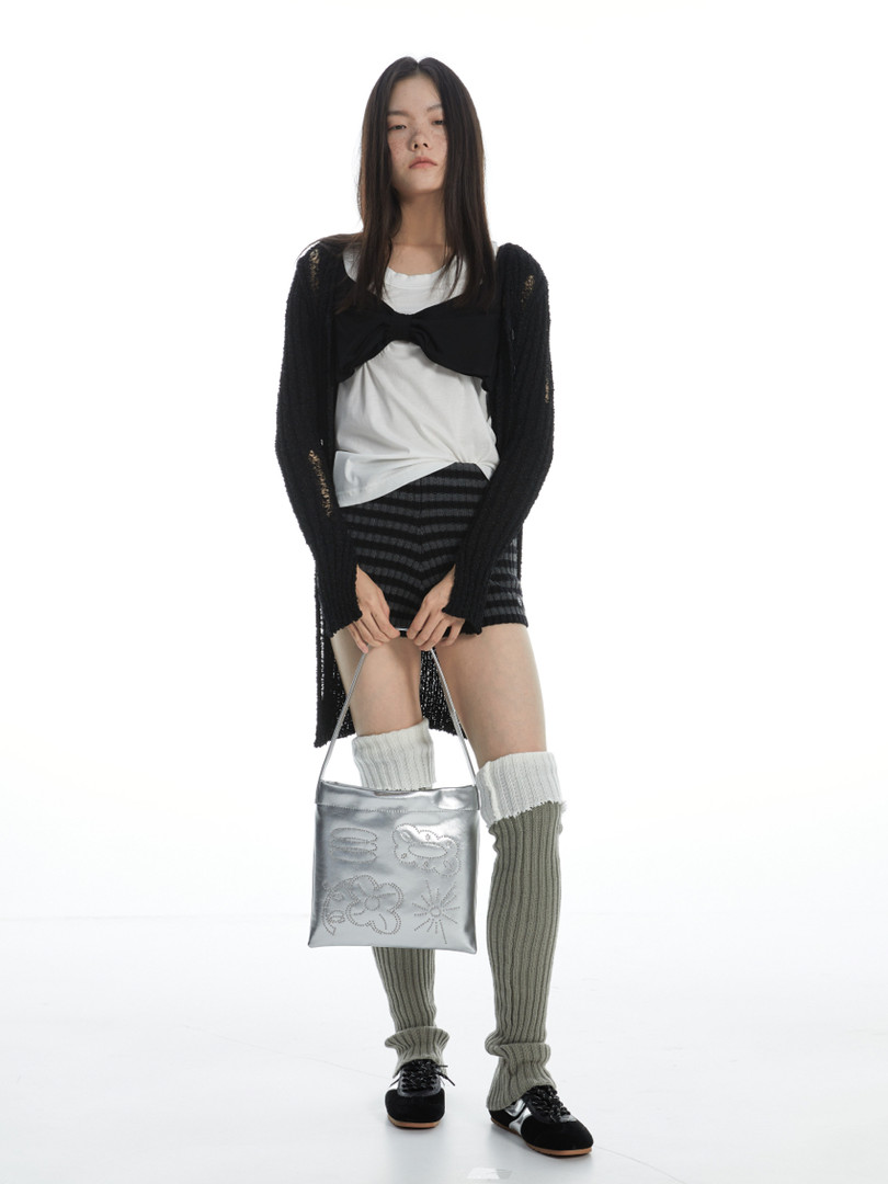 Fashion model wearing a black layered outfit with a silver handbag on a white background