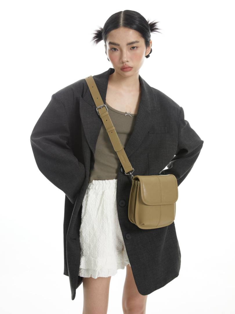 Model wearing an oversized black blazer with a tan crossbody bag