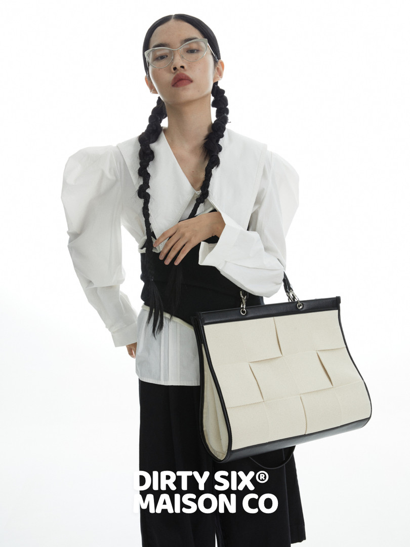 Model wearing a black-and-white handbag with a monochrome fashion outfit