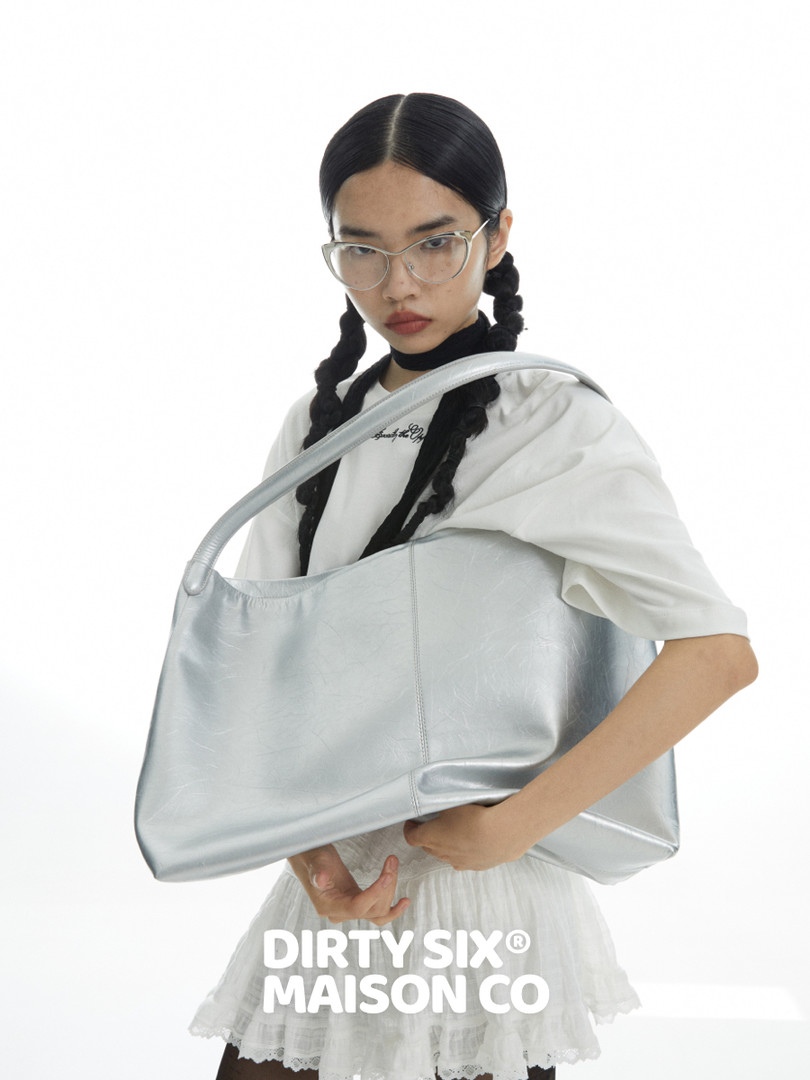 Silver oversized shoulder bag held by a model with brand text overlay