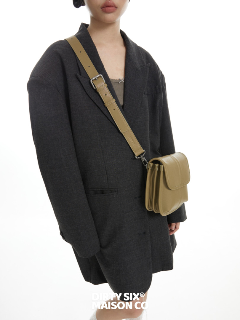 Model wearing a black oversized blazer with a beige crossbody bag
