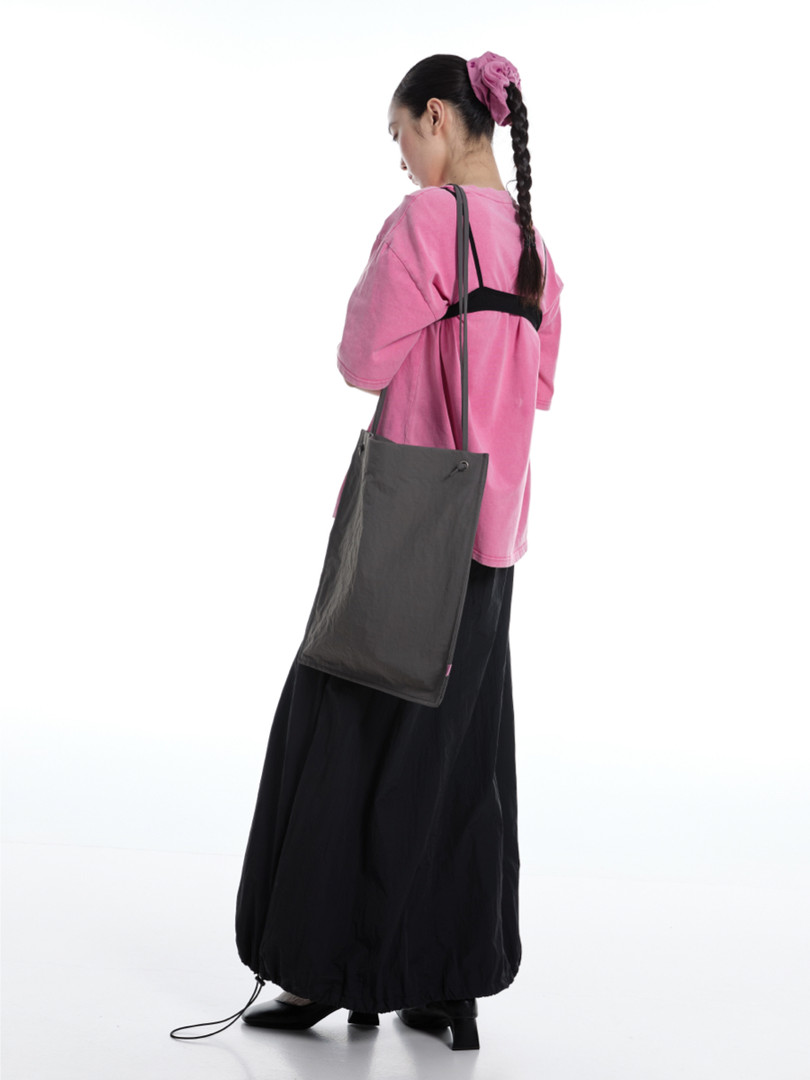 Model wearing a pink top and black skirt with a large black shoulder bag