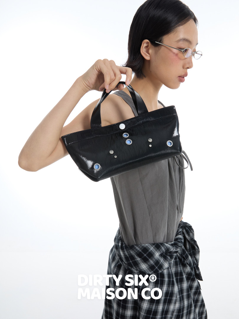 Black glossy mini handbag worn on model
