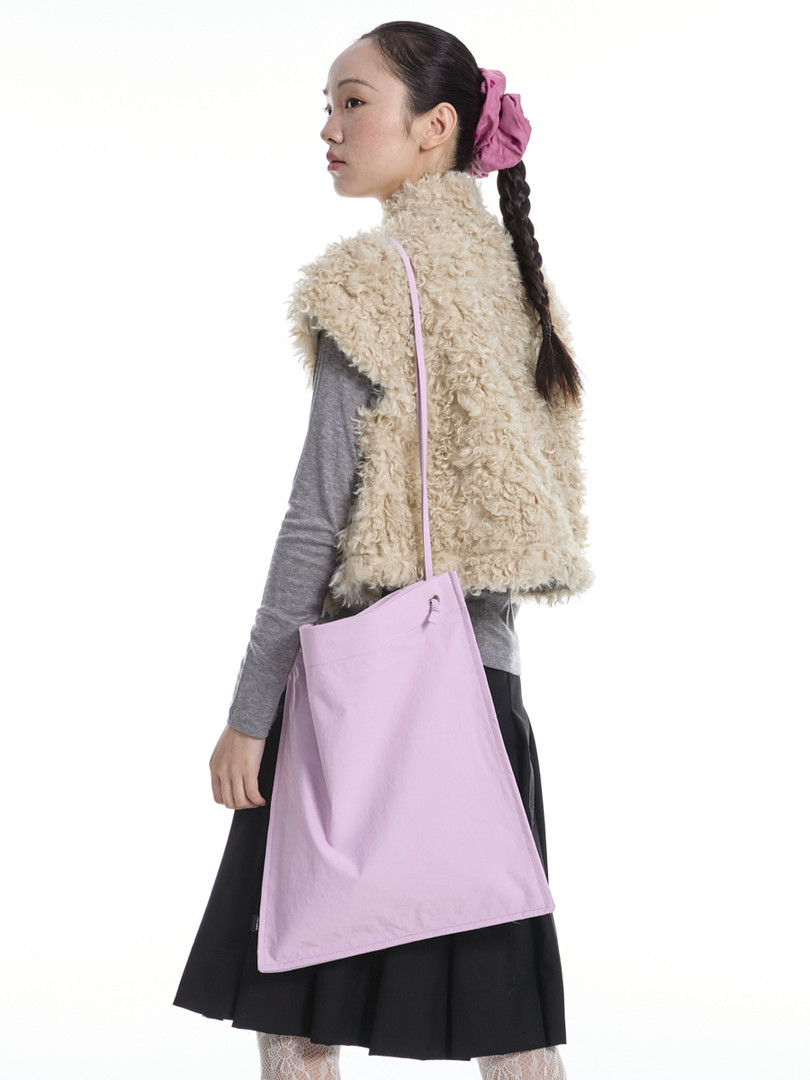 Model wearing a beige shaggy faux fur vest with a pink tote bag