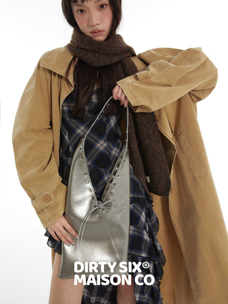 Model wearing a tan oversized trench coat with scarf and metallic handbag