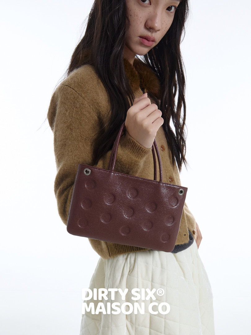 Model holding a burgundy textured handbag