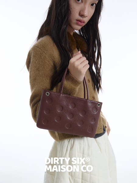 Model holding a burgundy textured handbag