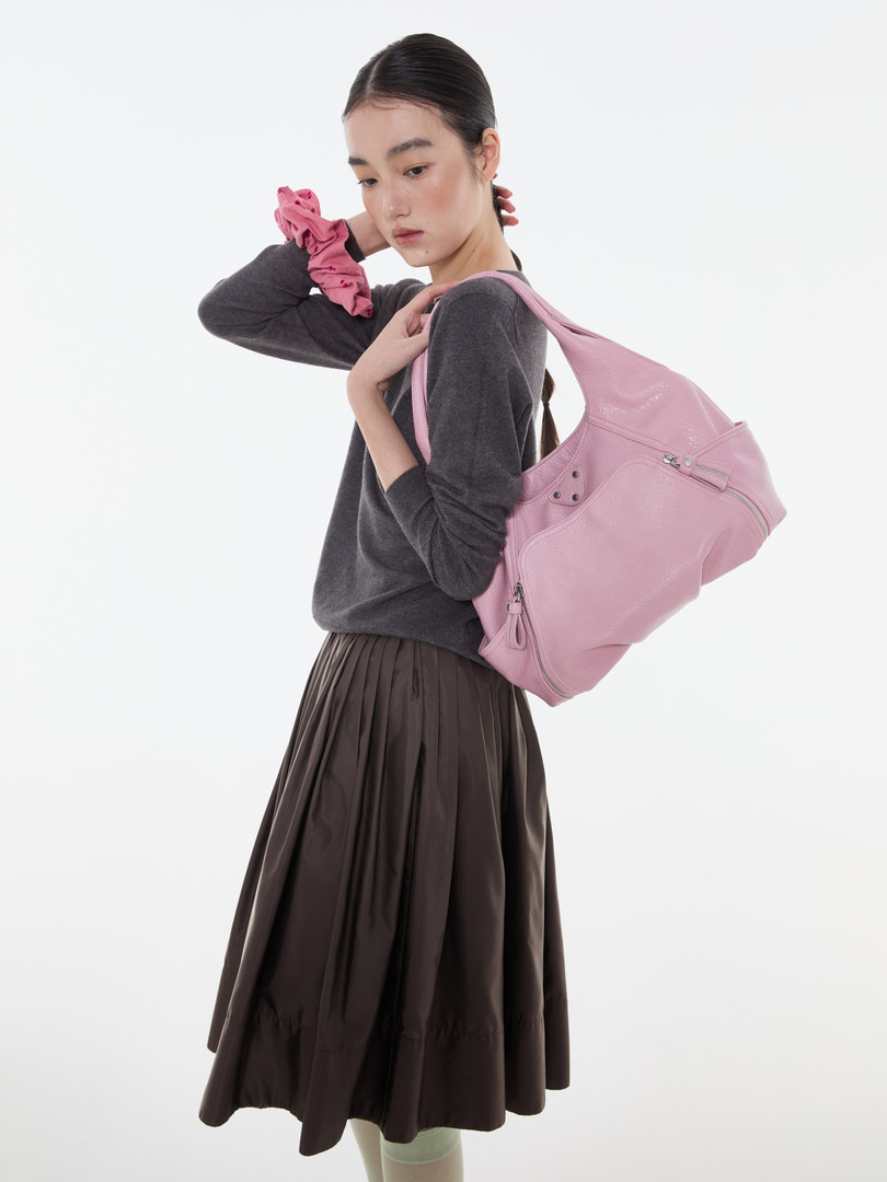Model wearing a pink shoulder bag with a dark outfit