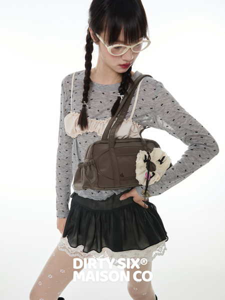 Fashion model wearing a gray top, black skirt, and brown shoulder bag