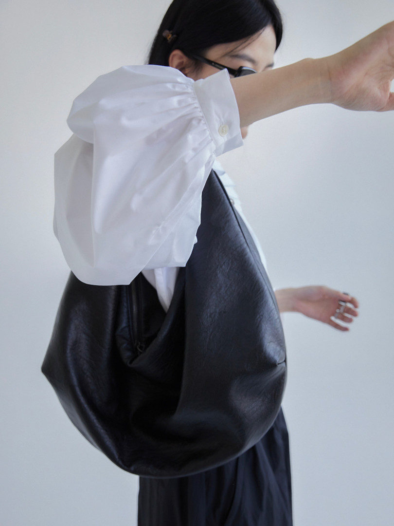 Black leather shoulder bag worn by a model