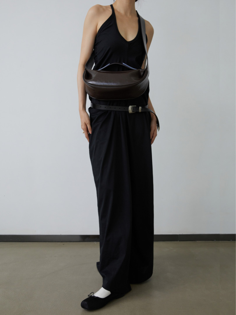 Model wearing a black halter top and wide-leg pants with a brown crossbody bag