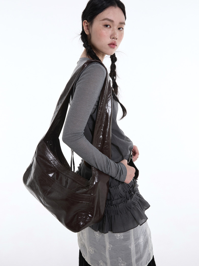 Model wearing a dark brown glossy oversized shoulder bag