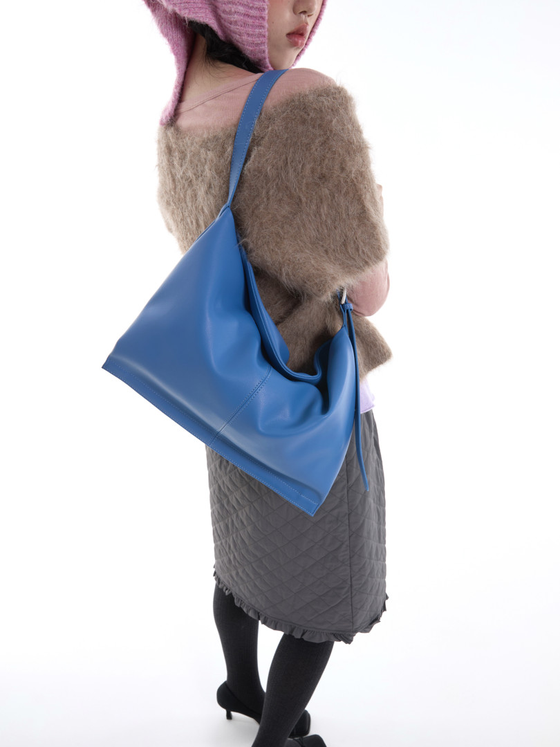 Model wearing a large blue shoulder bag with a fashion outfit