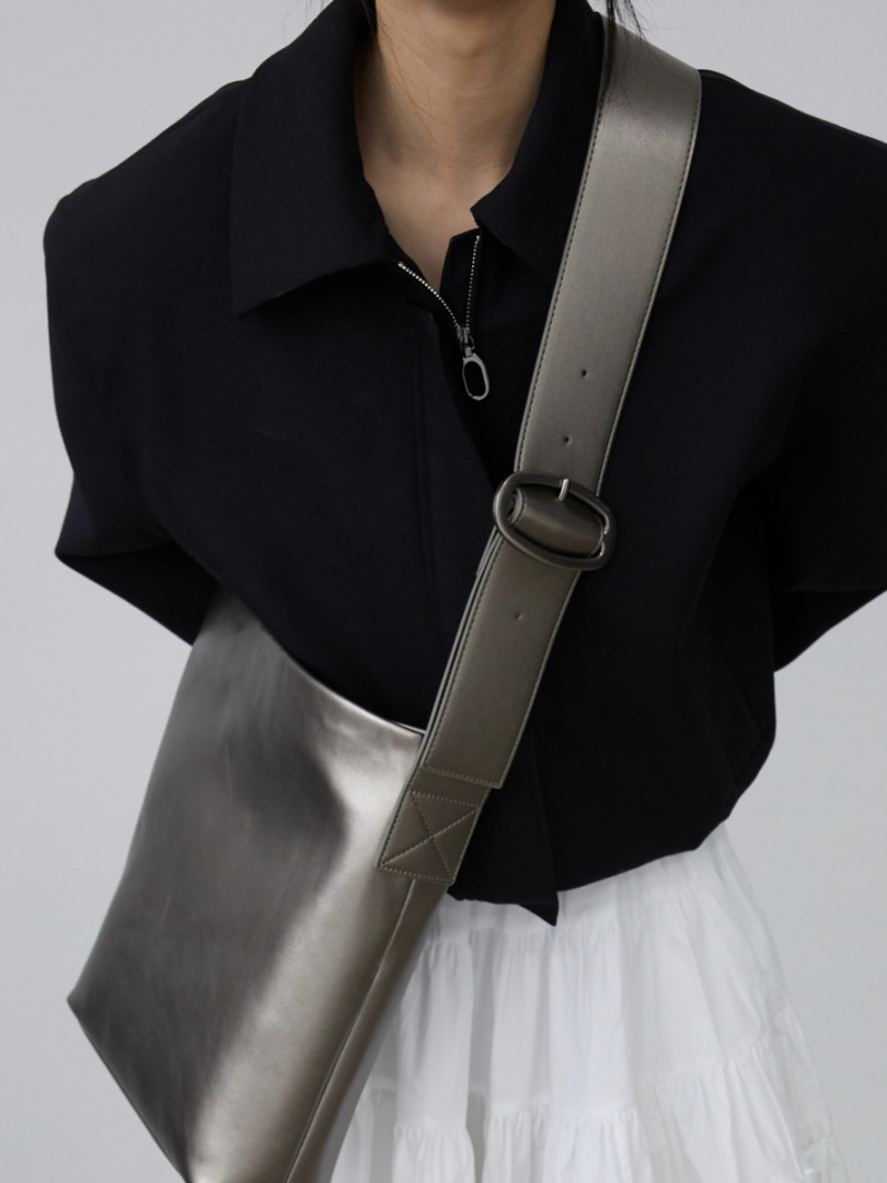 Metallic gray crossbody shoulder bag worn over a black outfit