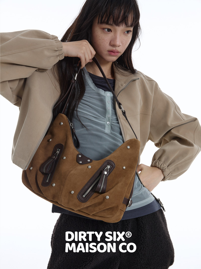 Model wearing a brown suede shoulder bag with zipper details
