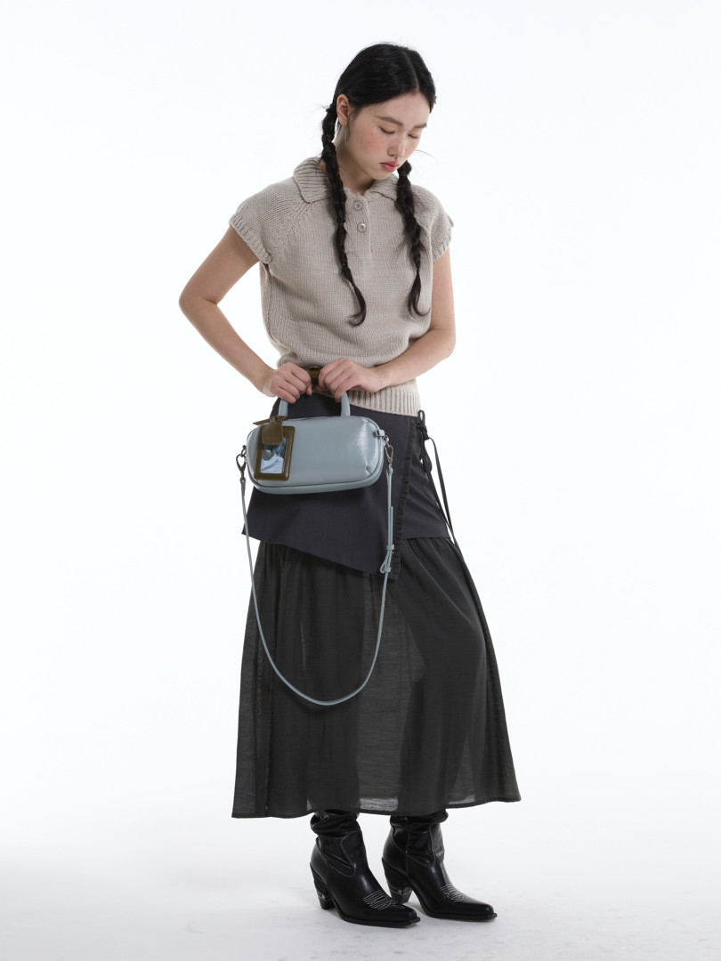 Model wearing a light blue handbag with a casual layered outfit