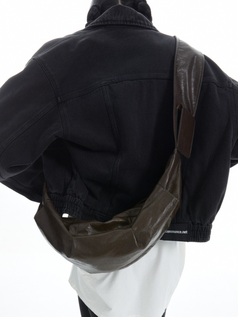 Black jacket worn with a brown leather shoulder bag on a model