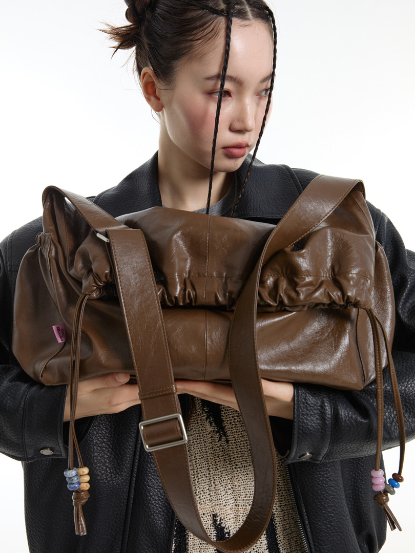 Brown leather shoulder bag held by a model